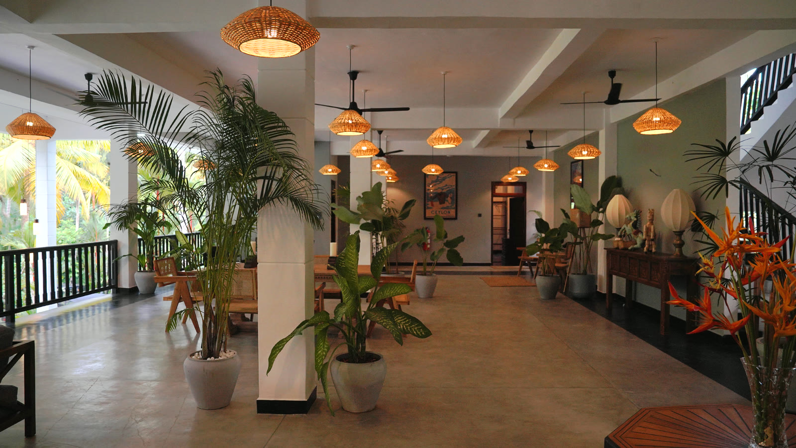 Open lobby with rattan lanterns and tropical plants at Breathe Collections