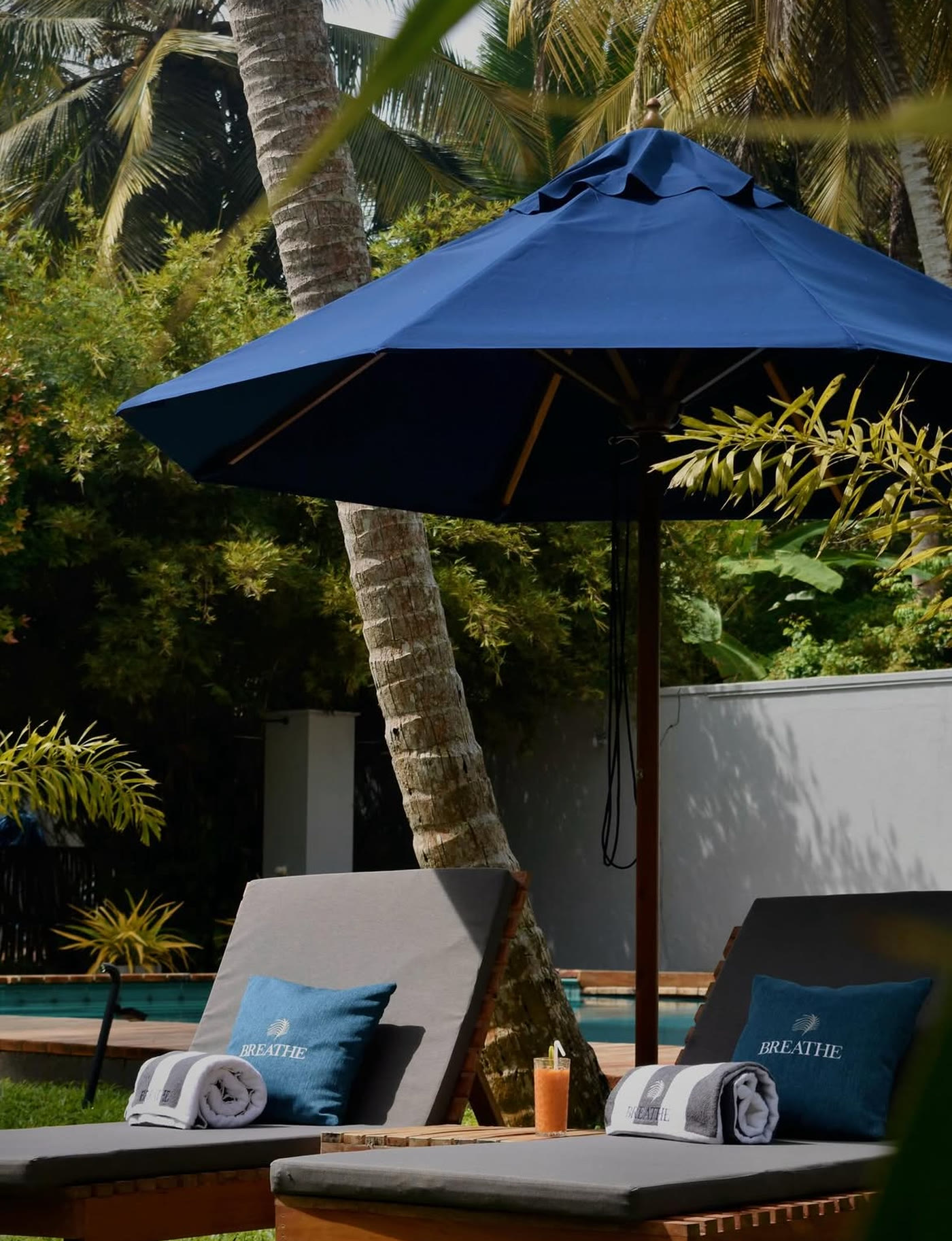 Poolside loungers with Breathe towels under a blue umbrella, Habaraduwa